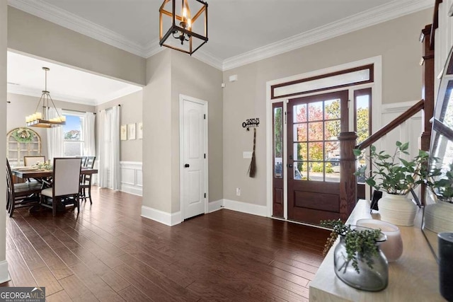 foyer entrance featuring dark hardwood / wood-style flooring, crown molding, and a chandelier