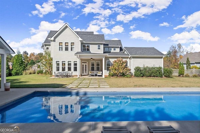 back of house featuring ceiling fan, a fenced in pool, a lawn, and a patio