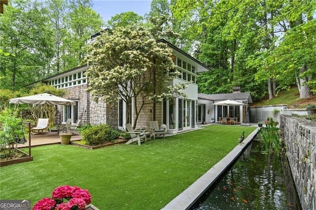 rear view of house featuring a sunroom and a yard