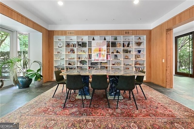 dining space with a wealth of natural light and wooden walls