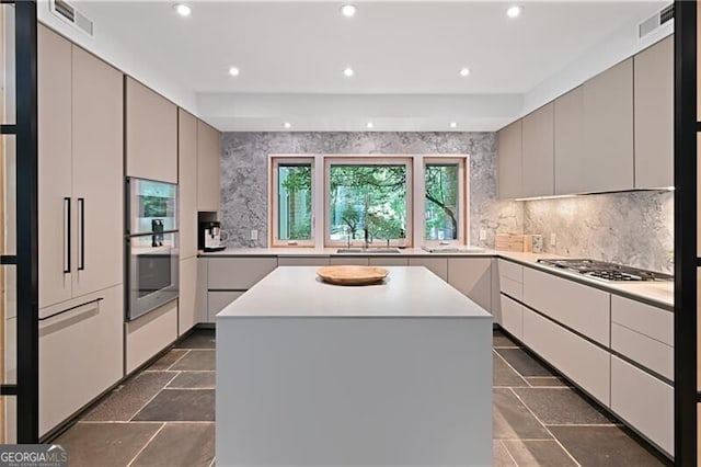 kitchen with tasteful backsplash, gray cabinetry, a center island, and stainless steel gas stovetop