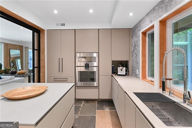 kitchen with plenty of natural light, stainless steel double oven, and sink