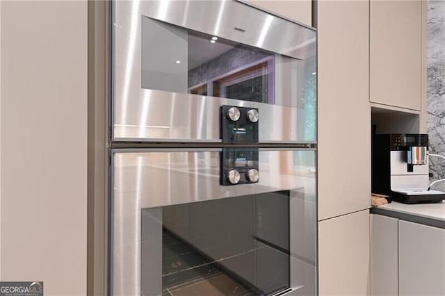 interior details with tasteful backsplash, white cabinetry, and double oven