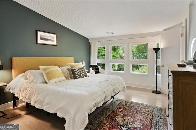 bedroom with wood-type flooring and vaulted ceiling