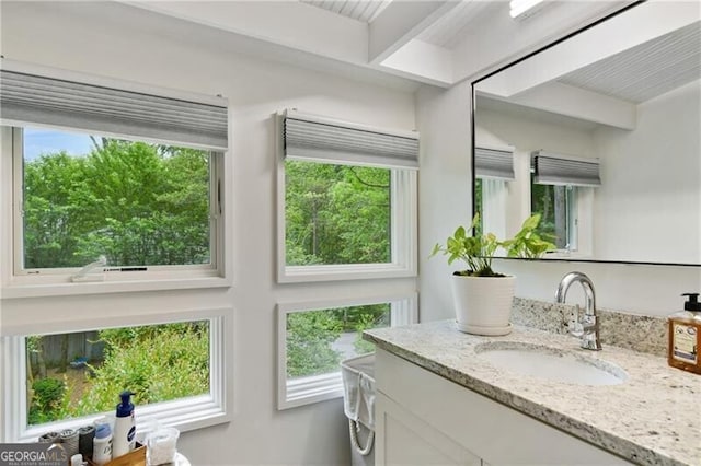 interior space featuring beam ceiling, vanity, and plenty of natural light