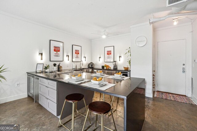 kitchen with kitchen peninsula, a kitchen breakfast bar, concrete flooring, ceiling fan, and crown molding