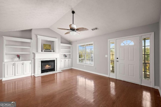 entryway with ceiling fan, dark wood-type flooring, a premium fireplace, a textured ceiling, and vaulted ceiling