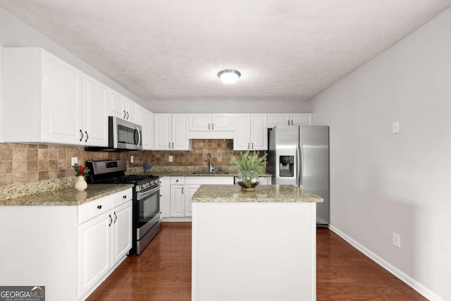 kitchen with sink, light stone counters, dark hardwood / wood-style flooring, white cabinets, and appliances with stainless steel finishes