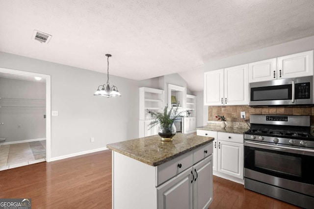 kitchen featuring a center island, dark wood-type flooring, a textured ceiling, white cabinets, and appliances with stainless steel finishes