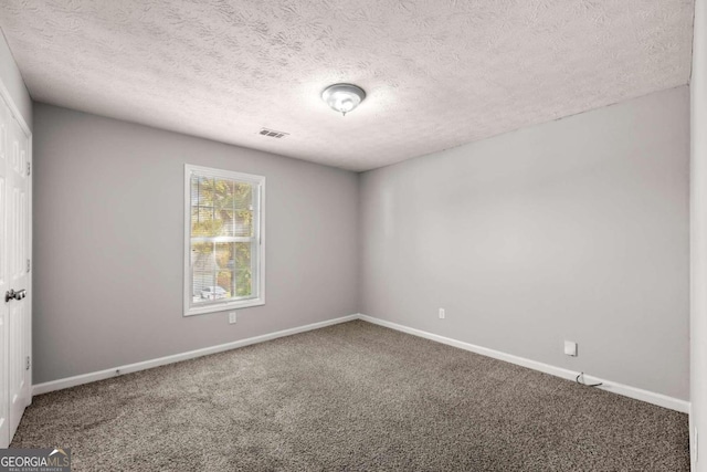 carpeted empty room with a textured ceiling