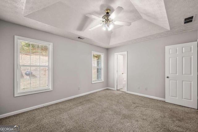 unfurnished bedroom featuring ceiling fan, carpet, and a raised ceiling