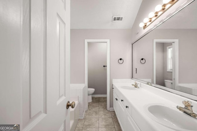 bathroom with a textured ceiling, vanity, tile patterned flooring, toilet, and lofted ceiling