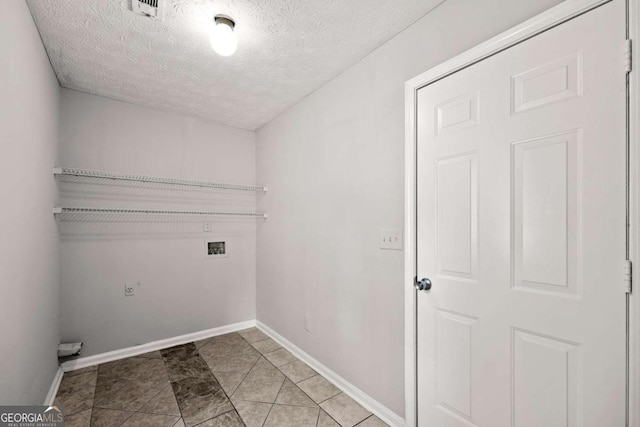 laundry area featuring hookup for a washing machine, light tile patterned flooring, and a textured ceiling