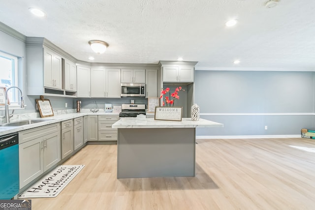 kitchen featuring crown molding, sink, light hardwood / wood-style flooring, gray cabinets, and appliances with stainless steel finishes