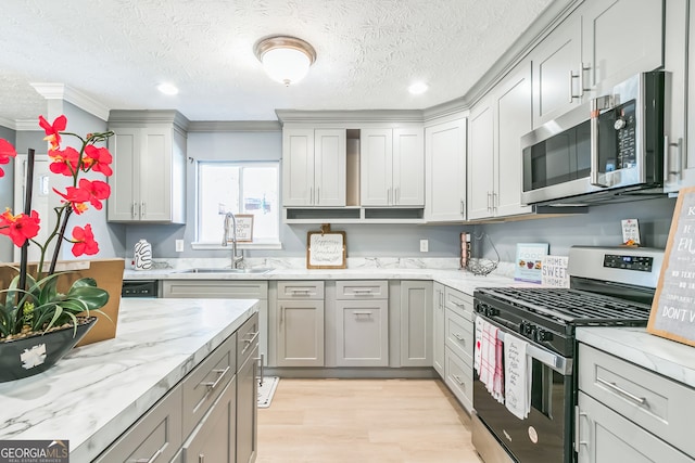 kitchen featuring a textured ceiling, light wood-type flooring, stainless steel appliances, and gray cabinets