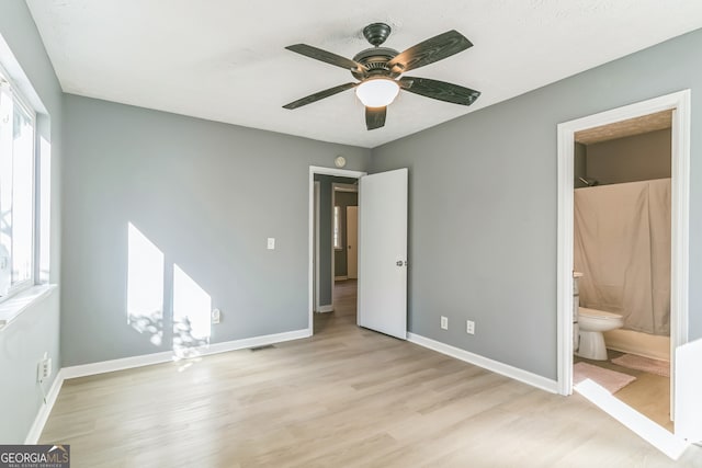 unfurnished bedroom with ceiling fan, light wood-type flooring, and ensuite bath