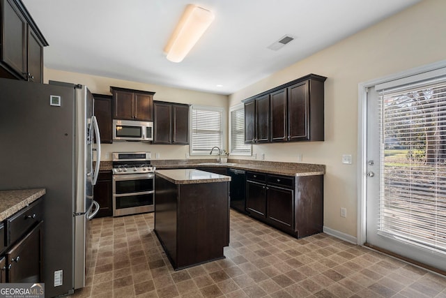 kitchen with dark brown cabinets, a kitchen island, sink, and stainless steel appliances