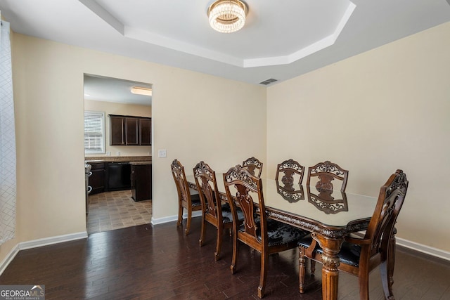 dining area featuring a raised ceiling and dark hardwood / wood-style flooring