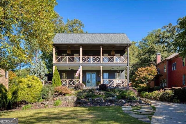 back of property featuring french doors, a yard, and a balcony