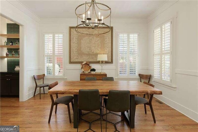 dining space with a notable chandelier, ornamental molding, and light hardwood / wood-style flooring