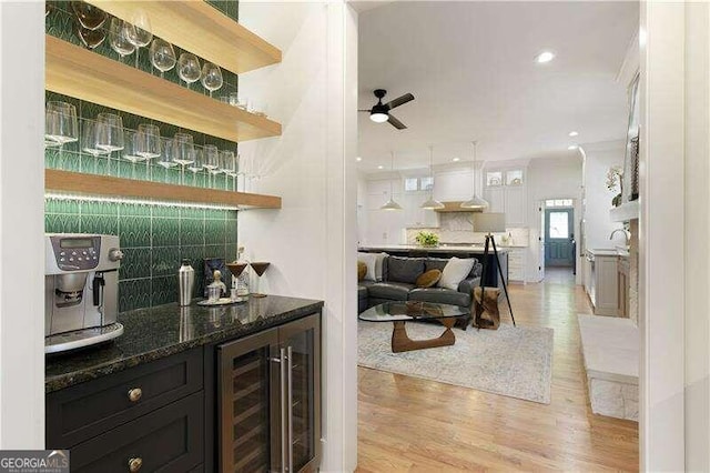 bar featuring ceiling fan, light hardwood / wood-style flooring, dark stone countertops, white cabinets, and wine cooler