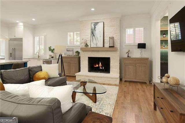 living room featuring plenty of natural light, ornamental molding, a fireplace, and light hardwood / wood-style flooring