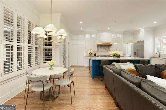 interior space with a notable chandelier, sink, crown molding, and light hardwood / wood-style flooring