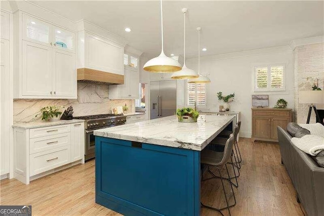 kitchen featuring white cabinetry, a center island, light hardwood / wood-style floors, decorative light fixtures, and high end appliances