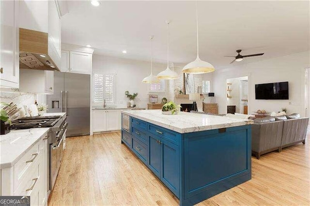 kitchen with custom exhaust hood, premium appliances, blue cabinets, decorative light fixtures, and white cabinets