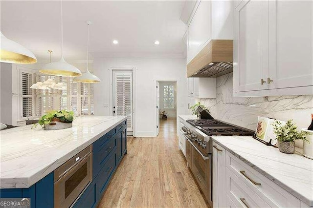 kitchen featuring white cabinets, hanging light fixtures, light stone countertops, light wood-type flooring, and stainless steel appliances