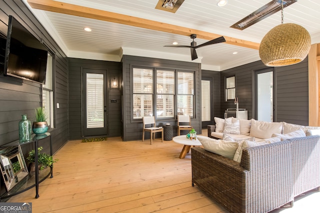 living room featuring ceiling fan, crown molding, wooden walls, beam ceiling, and light hardwood / wood-style floors