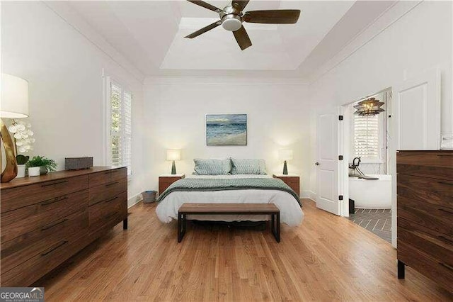 bedroom with a raised ceiling, ceiling fan, ornamental molding, and light wood-type flooring