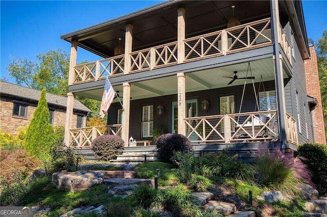 rear view of property featuring ceiling fan, covered porch, and a balcony