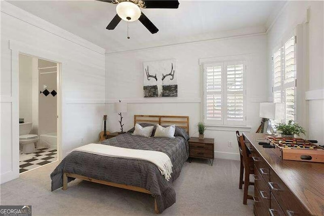 carpeted bedroom with ensuite bath, ceiling fan, and ornamental molding