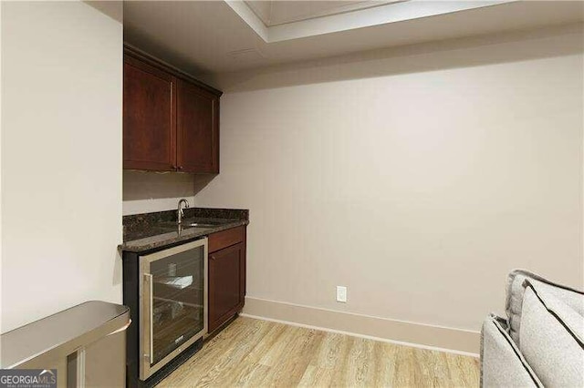 bar featuring dark brown cabinets, light hardwood / wood-style floors, wine cooler, and sink