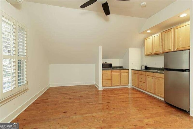 kitchen with stainless steel fridge, light wood-type flooring, lofted ceiling, and light brown cabinets