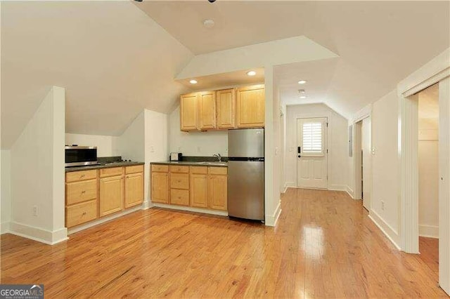 kitchen featuring sink, vaulted ceiling, light brown cabinetry, appliances with stainless steel finishes, and light wood-type flooring