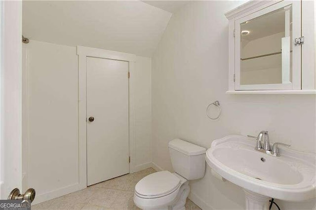 bathroom featuring tile patterned floors, sink, vaulted ceiling, and toilet