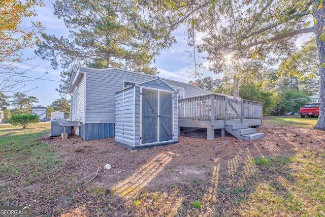 rear view of house featuring a shed and a wooden deck