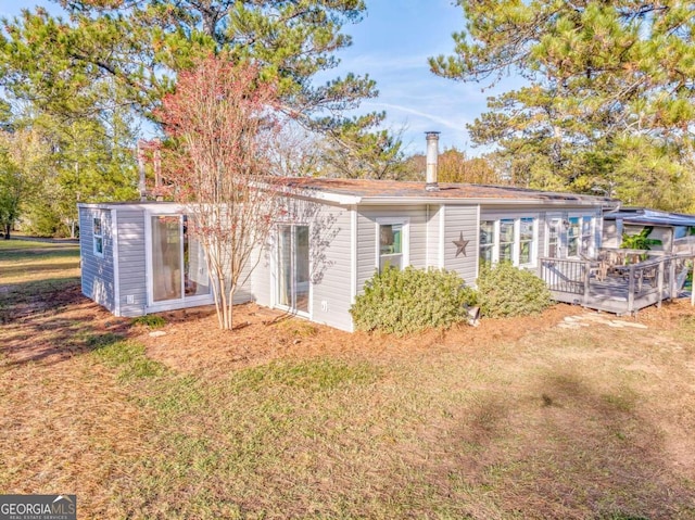 rear view of property featuring a lawn and a wooden deck