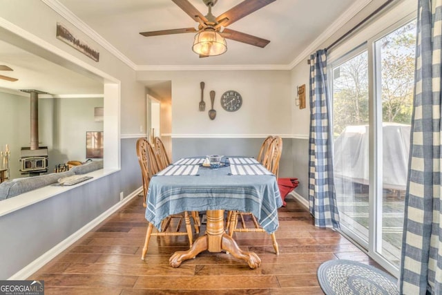 dining room with a wood stove, crown molding, ceiling fan, and hardwood / wood-style flooring