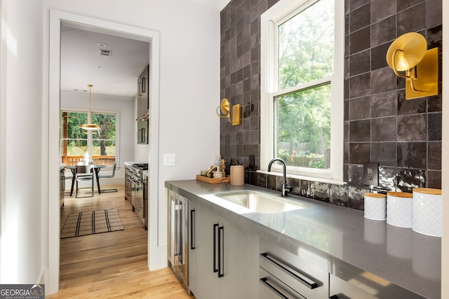 kitchen featuring plenty of natural light, light hardwood / wood-style flooring, high end stainless steel range, and sink