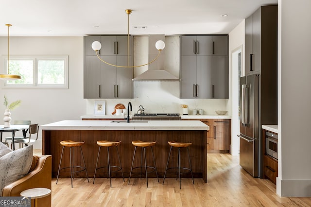 kitchen featuring a kitchen breakfast bar, light hardwood / wood-style flooring, hanging light fixtures, and stainless steel appliances