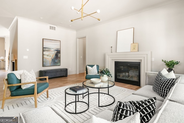 living room with light hardwood / wood-style floors, crown molding, and a chandelier