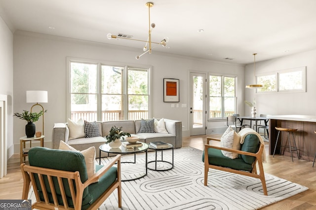 living room featuring a wealth of natural light, light hardwood / wood-style flooring, ornamental molding, and an inviting chandelier