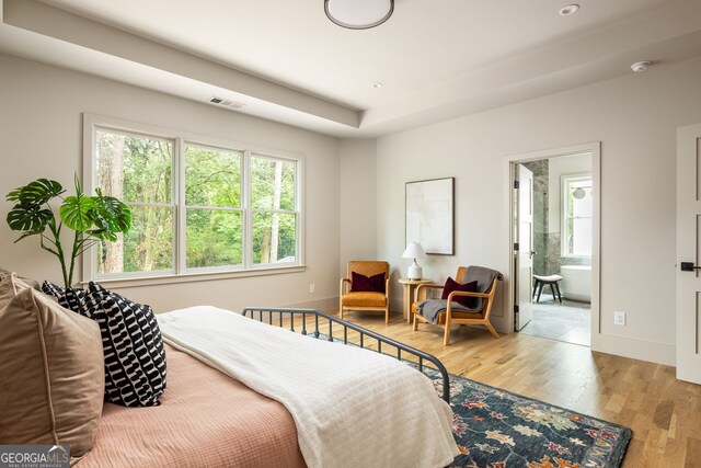 bedroom with ensuite bathroom and light hardwood / wood-style floors