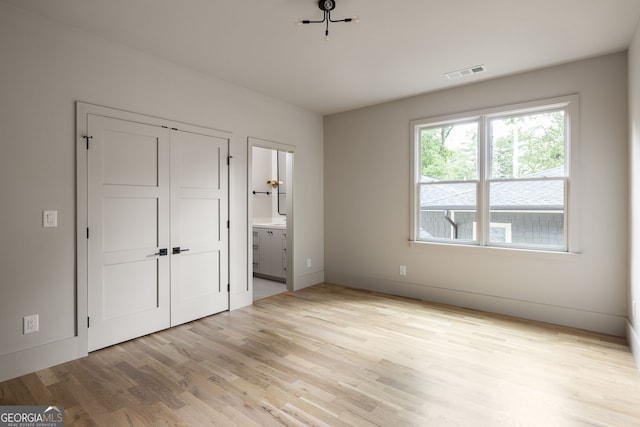 unfurnished bedroom with connected bathroom and light hardwood / wood-style floors