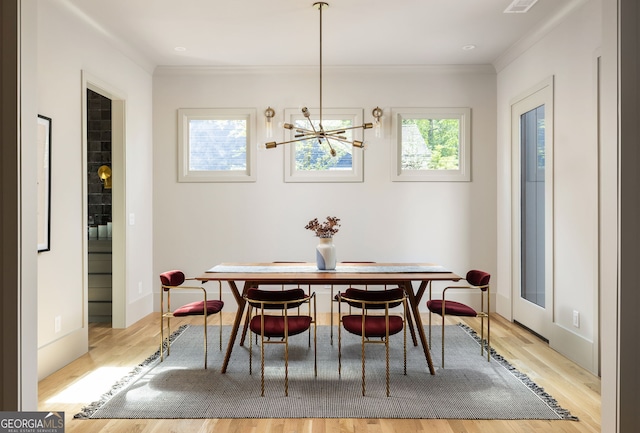 dining area with crown molding, light hardwood / wood-style flooring, and a chandelier