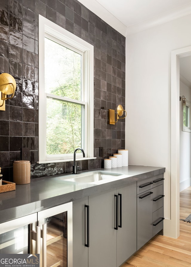 bar with gray cabinetry, plenty of natural light, light hardwood / wood-style floors, and sink