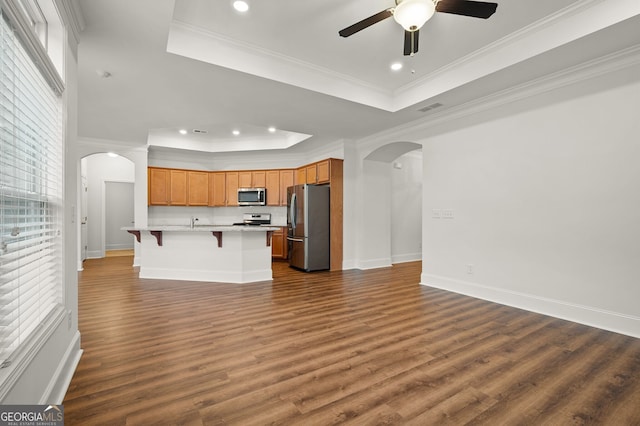 kitchen featuring a center island with sink, appliances with stainless steel finishes, dark hardwood / wood-style floors, and a raised ceiling